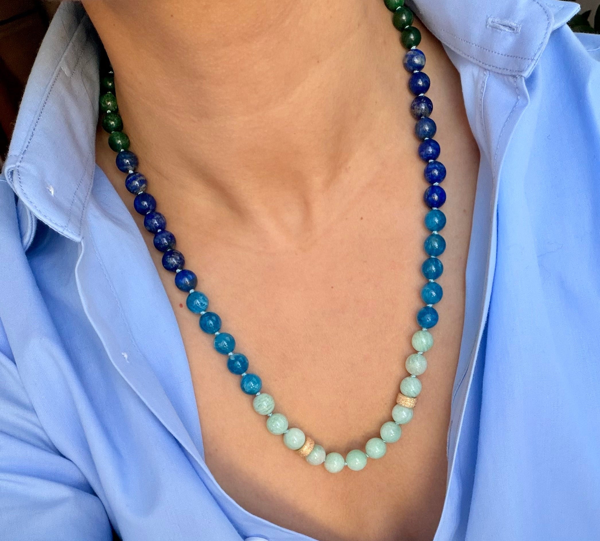 Person wearing a long beaded necklace with a blue shirt