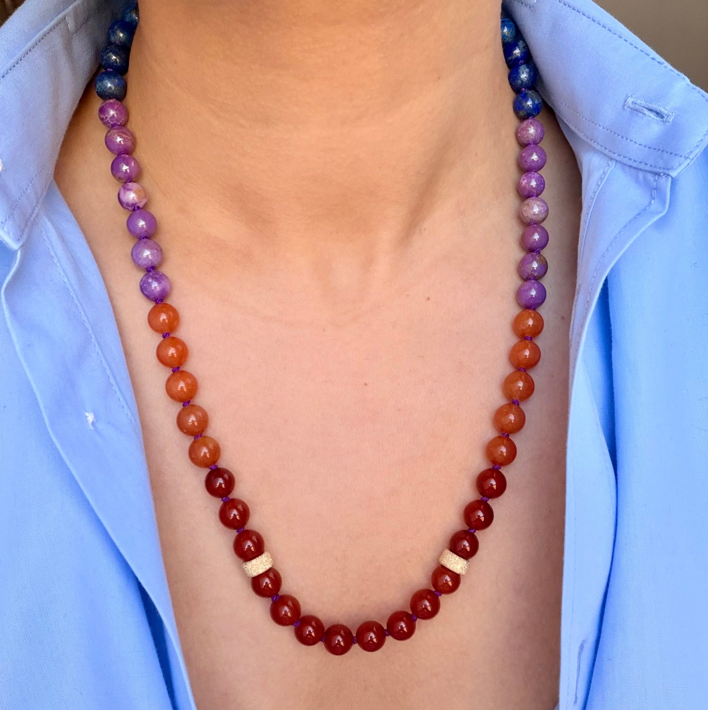 Necklace with multicolored beads worn by a person wearing a light blue shirt.